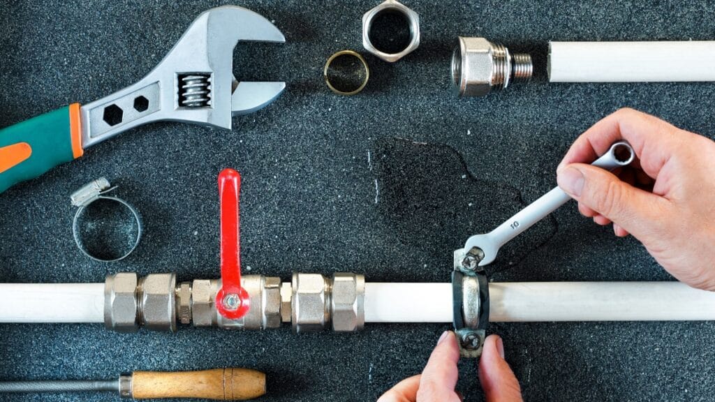 Plumber repairing a pipe valve with an adjustable wrench in Winter Garden