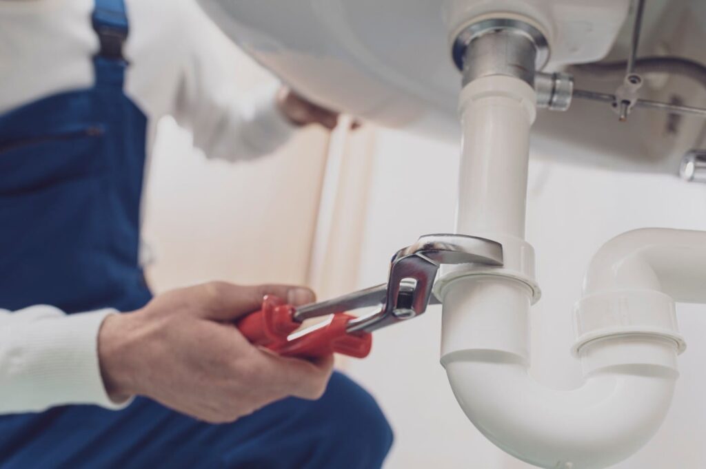 Plumber repairing a white drain pipe beneath a sink in Winter Garden