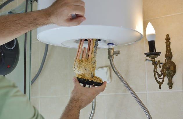 Technician removing mineral buildup from a water heater in Winter Garden