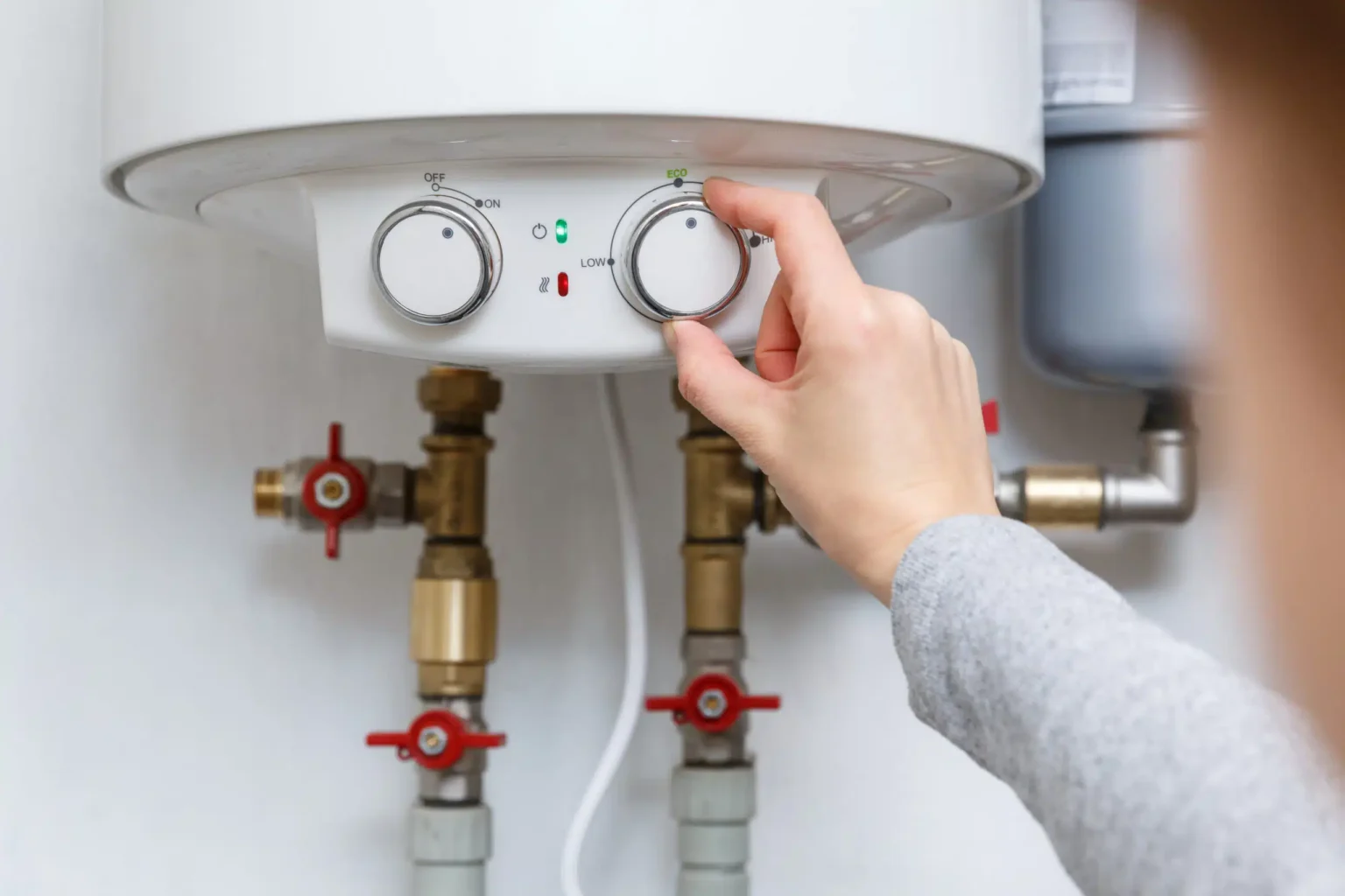 Homeowner adjusting the temperature controls on a water heater in Winter Garden